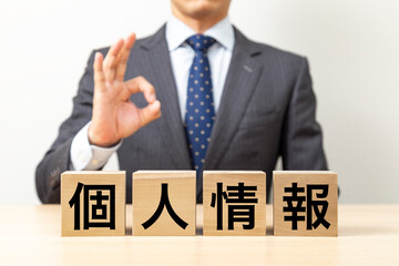 「個人情報」と書かれたブロックとOKポーズをするビジネスマン