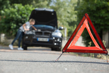 triangle on floor with woman looking at breakdown car