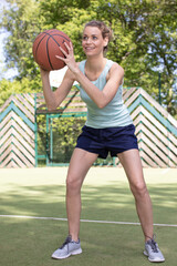 Fototapeta premium attractive female holding a basketball while playing outdoors