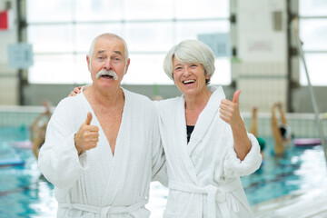 senior couple with thumbs up by the pool
