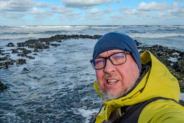 Joyful seaside photograph, Authentic outdoor portrait of cheerful explorer amidst basalt rocks and coastal scenery