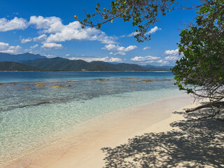 Idyllic tropical beach landscape with crystal clear waters, white sand and mountain views