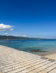 Fototapeta premium Mountain and ocean views from a wooden pier under a clear blue sky