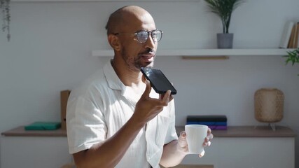 Video of businessman sending audios with smartphone while standing near the window in the office - Powered by Adobe