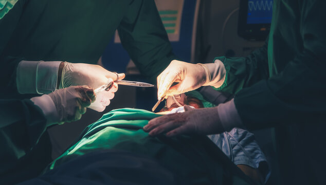 Professional Medical Doctors and team performing surgical operation in bright Modern operating room with lighting equipment in hospital.