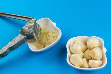 Freshly Minced Garlic with Garlic Press on Blue Background