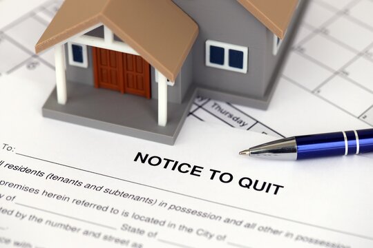 Generic toy house and eviction notice or notice to quit on table close up