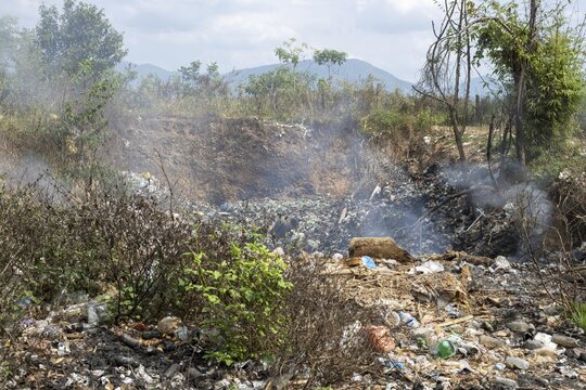 Coking rubbish dump, rubbish pit with waste and plastic rubbish, karst landscape near Vang Vieng, Vientiane province, Laos