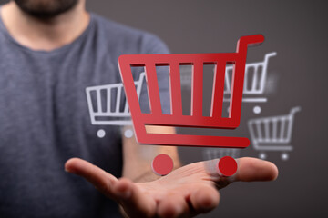 Concept of online shopping and e-commerce with hand holding a 3D shopping cart. Represents buying,...