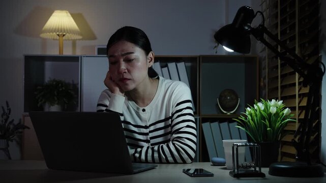 sleepy woman yawning while working with laptop at a night