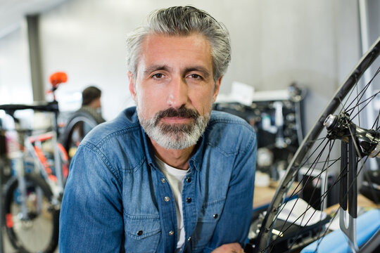a man working in a bicycle repair shop posing