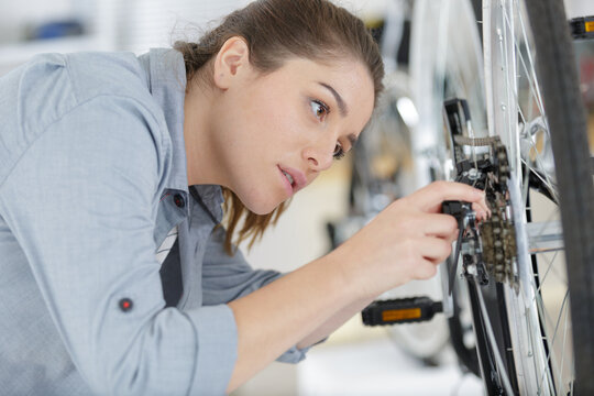 female bicycle mechanic repairing wheel in a workshop - Powered by Adobe
