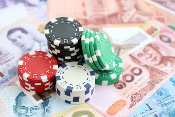 Thai baht currency money bills and bunch of casino chips close up. The concept of gambling and casino games