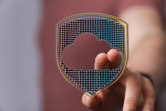 Abstract image showing cloud security and data protection. Person touching a digital shield representing secure cloud storage and cyb