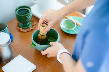 Hands whisking matcha. A Japanese traditional green tea. The calming ritual of authentic tea preparation, from above