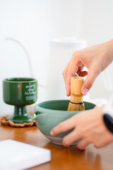 Cooking green matcha tea during the Japanese ceremony. Traditiobal kit, Bamboo whisk and beverage, spoon shashaku, heated tea bowl known as a chawan. Horizontal image.