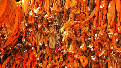 Saffron ribbons tied by devotees to trees as a sign of faith at temples in Gokul, Mathura, Uttar...