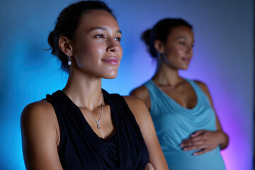 Two women stand together, one expecting and the other proudly supporting, representing friendship, life transitions, and the beauty of shared experiences in motherhood.