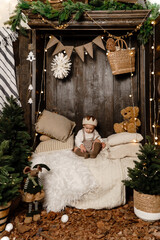 A boy like a little king sits in a New Year's interior like in a fairy tale