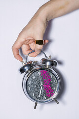 Male hand holding metallic alarm clock