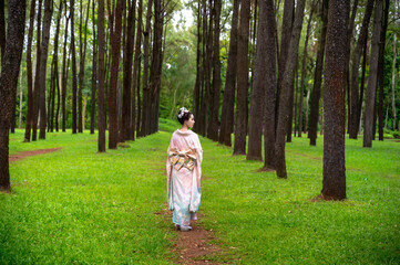 Fototapeta premium Young pretty Japanese woman in elegant traditional kimono or yukata walking in garden