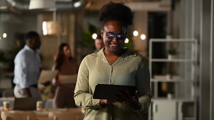 African american businesswoman using digital tablet in modern office at night - Powered by Adobe