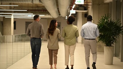Diverse business colleagues walking and talking in modern office corridor