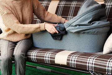 young mother carries the cradle with the child to the garden swing