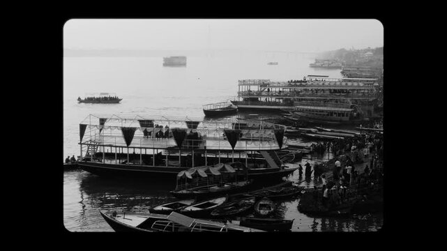 Classic black and white view of Varanasi&rsquo;s ghats with boats docked along the Ganga River and people gathered by the shore. A timeless capture of India&rsquo;s spiritual and cultural heritage.