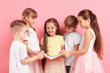Cute little kids reading book on pink background