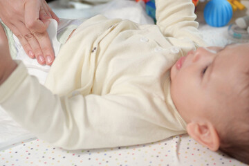 Mother changing her baby diaper on table, close up