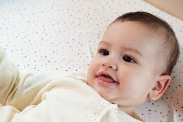 Happy newborn baby makes a funny face. Portrait of a crawling baby in his room close up