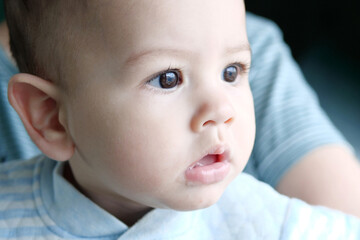 Happy newborn baby makes a funny face. Portrait of a crawling baby in his room close up
