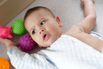 Happy newborn baby makes a funny face. Portrait of a crawling baby in his room close up