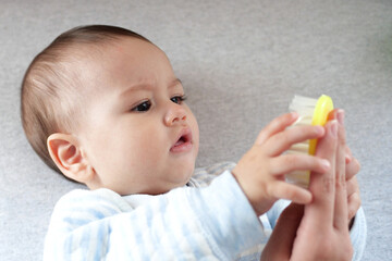 Young mother hand holding comb and brushing her baby. Close up Mother care. Concept of parenthood