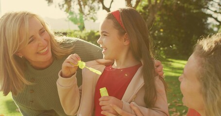 Playing with bubbles, generations gathering in park, girl in red dress holding yellow wand, bottle