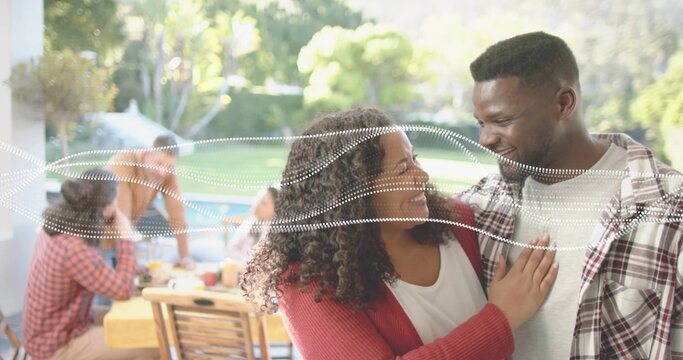 Smiling couple standing close in backyard, wearing red cardigan and plaid shirt near picnic table