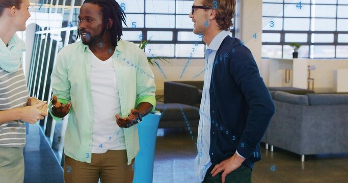 Talking three coworkers wearing green shirt, navy cardigan, holding yellow notepad in office lounge