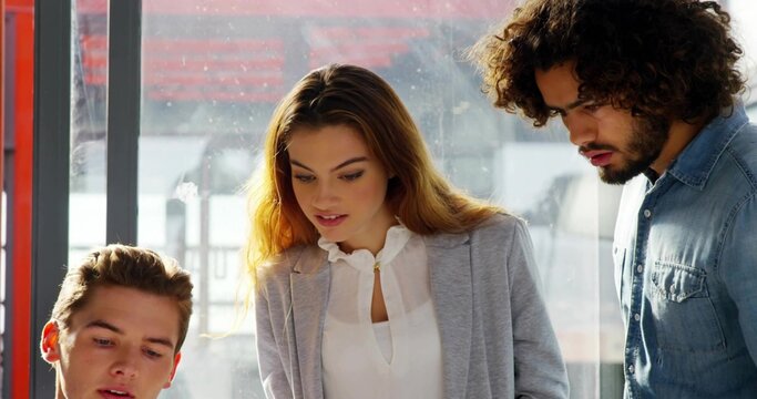 Leaning woman in grey blazer, man in denim shirt studying at office window with red frame - Powered by Adobe