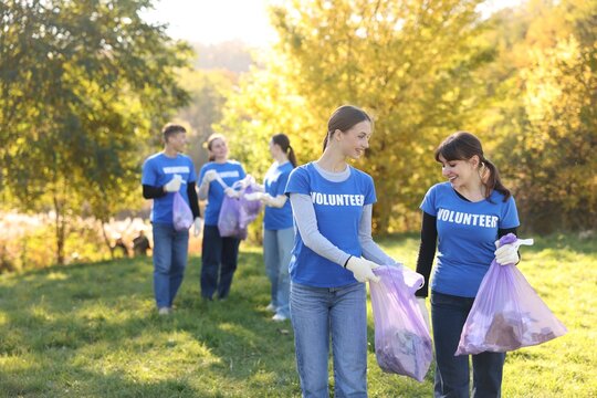 Group of happy volunteers with bags of trash in park