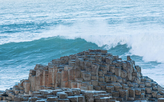 Dramatic waves crash over the Giant’s Causeway, Northern Ireland – rugged coastal basalt columns landscape”