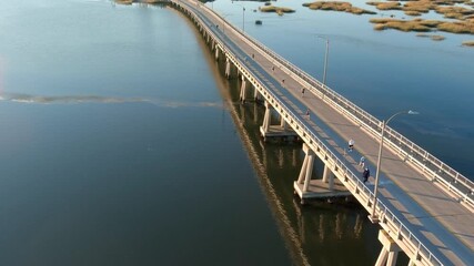 Aerial view of people running a marathon over a bridge at sunrise.
