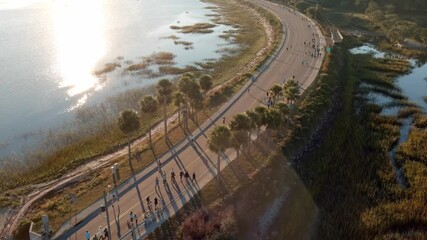 Tracking aerial drone shot of a running race during early morning with lens flare.
