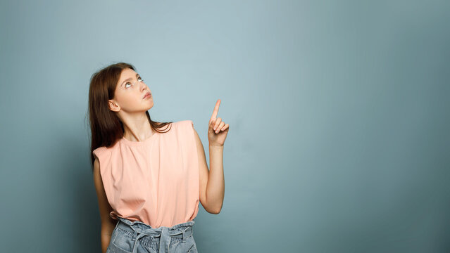 Young woman looking and pointing up with thoughtful expression