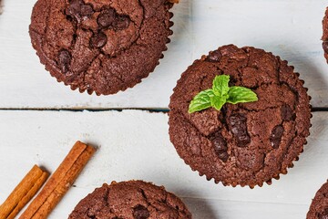 Delicious chocolate muffins with mint garnish and cinnamon sticks