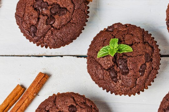Delicious chocolate muffins with mint garnish and cinnamon sticks