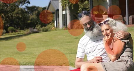 Mature couple sitting on low curb, man leaning, orange overlays shifting, camera zooming, marketing - Powered by Adobe