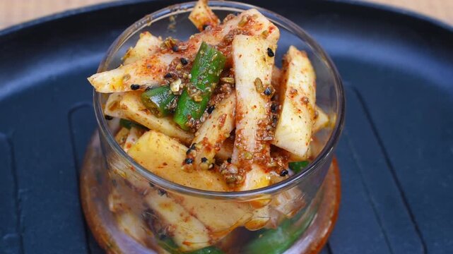 Homemade Mooli Hari Mirch Achar that is Radish and Green Chili Pickle served in a glass jar placed on a black rustic tray. zoom view