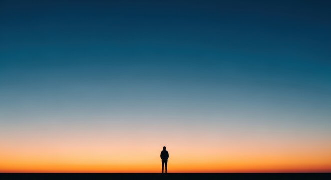 Lone silhouette of a person standing with arms raised in triumph against a vibrant sunset sky