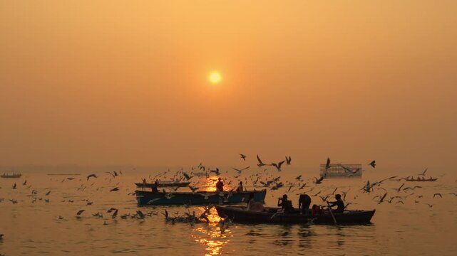 Tourists enjoy an early morning boat ride on the Ganga River in Varanasi as birds fly gracefully across the golden sky. A perfect mix of peace, culture, and spirituality in India&rsquo;s holiest city.